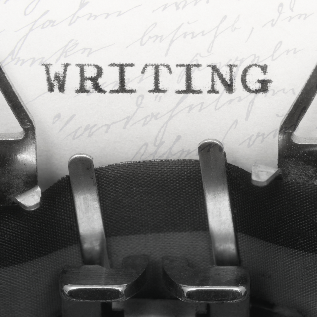 A typewriter has typed the word WRITING on a white piece of paper