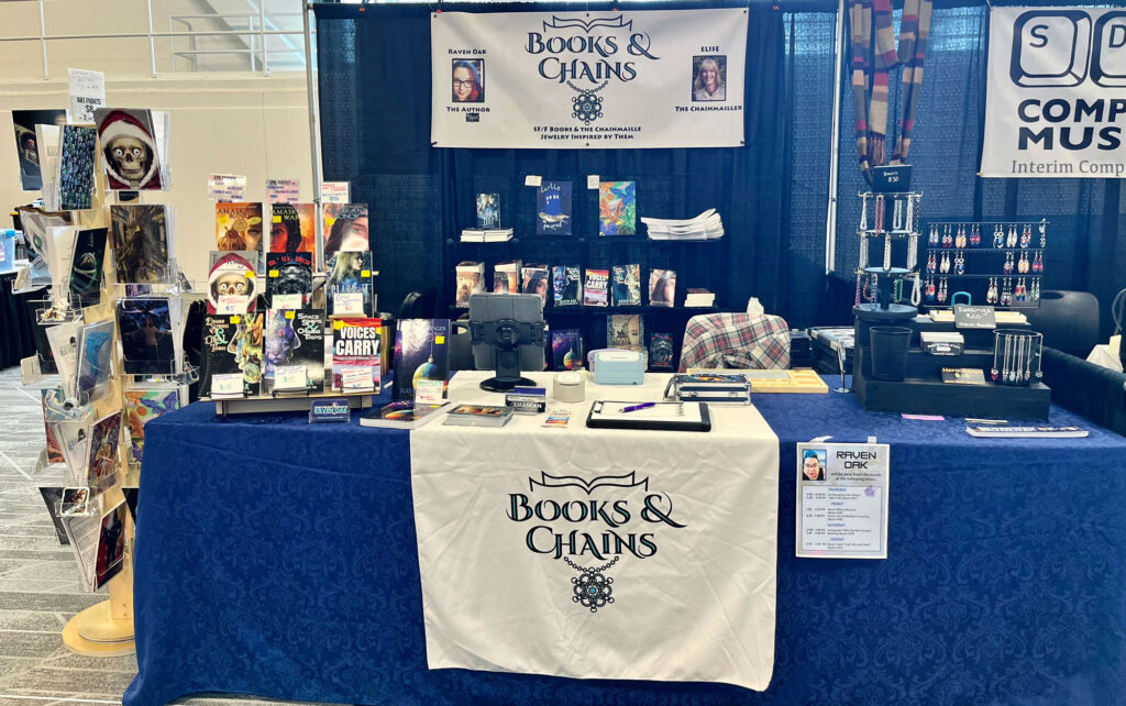 The front view of our booth (Books & Chains) with all of our books, art, and chainmaille jewelry. 